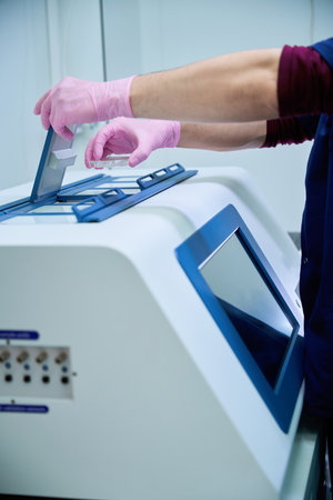 Gloved hand operating control panel on cryopreservation unit