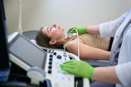 Focused doctor conducting neck ultrasound on patient lying down