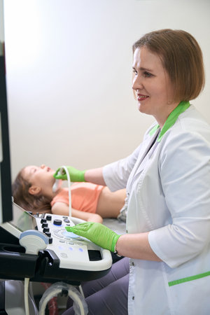 Doctor performing ultrasound scan on child neck