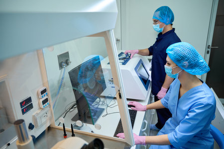 Doctors inspect analysis data and adjust lab equipment settings.の写真素材