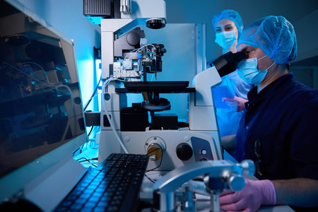 Two embryologists working with a micro-manipulation system