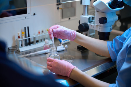 Embryologist handling lab samples under a microscopeの写真素材