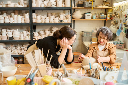 Two women, one young and one old, chat in ceramics studioの写真素材