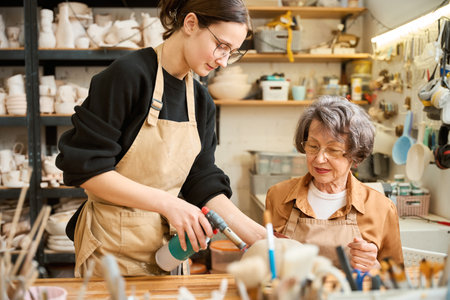 Young woman teaches elderly lady how to work with clayの写真素材
