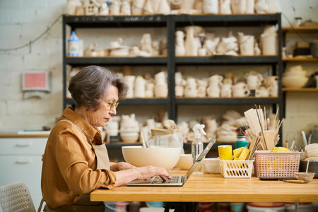Lady is sitting at a table and working on laptopの写真素材