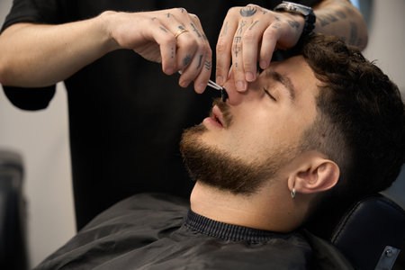 Barber use wax to tidy up client nasal hairの写真素材
