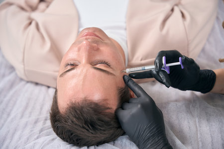 Cosmetologist making filler injections to male client to remove wrinklesの写真素材