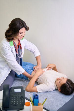 Female in a medical uniform examines the patients abdomen