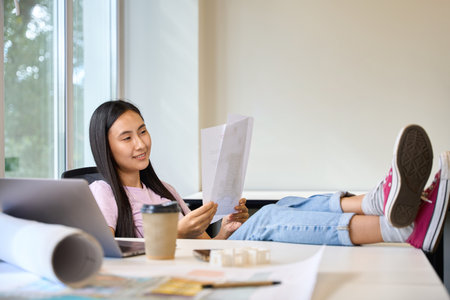 Woman comfortably settled into her workplace in a bright roomの写真素材