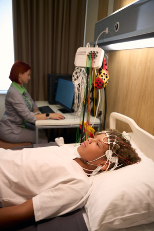 Patient lies in bed with EEG electrodes attachedの写真素材