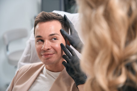Woman cosmetologist examining male client face skin on presence of wrinklesの写真素材