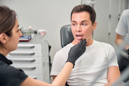 Female dentist finding gums inflammation during male patient examination