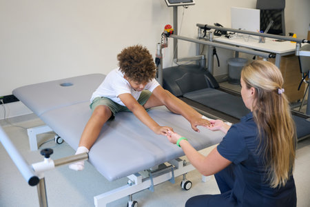 Young physiotherapist guides the patient through a leg extension exercise