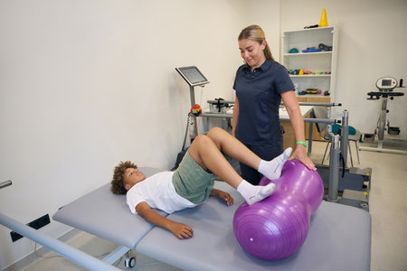 Teenage boy practices leg movements on therapy table