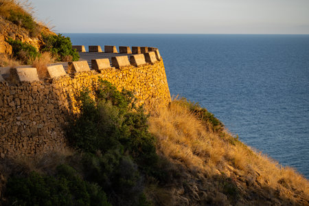 Serene coastal view of stone wall and sea at sunsetの写真素材