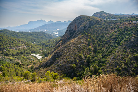 Serene mountain range with winding road and lush vegetationの写真素材