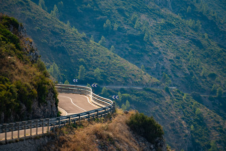 Winding mountain road with guard rails and directional signs