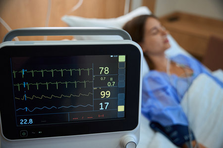 Modern heart rate monitor in hospital with female patient in backgroundの写真素材