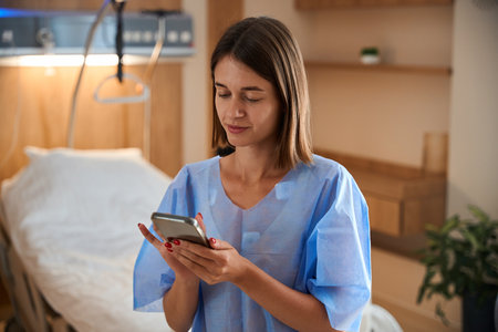 Woman patient using smartphone while seated in hospital clinic