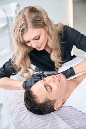 Young man doing face lifting in aesthetic clinic