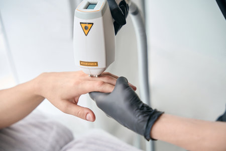 Cropped photo of beauty master working with laser device for manの写真素材