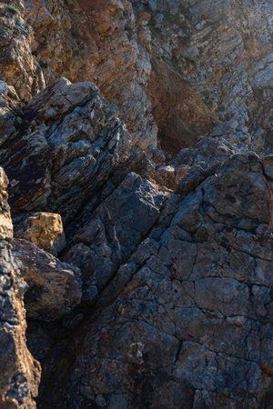 Textured rock formations along the shoreline of Adraga Beach in Portugal under natural lightの写真素材