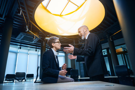 Engaged conversation between man and woman in modern officeの写真素材