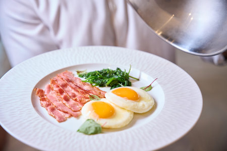 Appetizing breakfast plate with fried eggs and bacon indoors