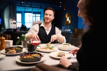 Smiling man dining with woman in cozy restaurant at evening
