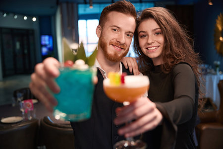 Young adults celebrating with cocktails at a bar in the evening