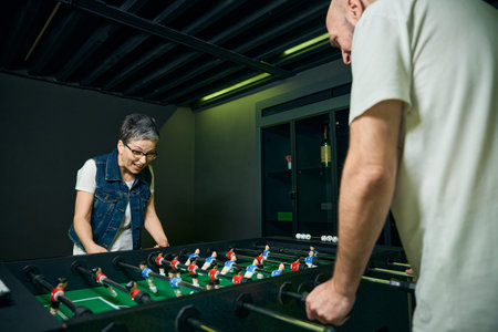 Adult woman and man playing foosball in game roomの写真素材
