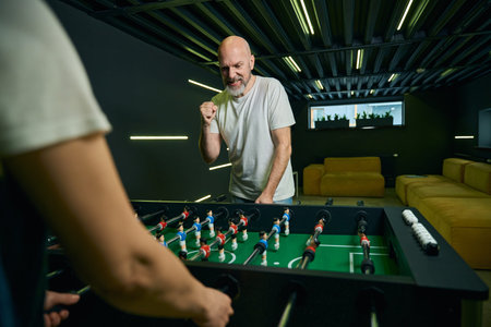 Middle-aged Caucasian men playing foosball in modern lounge