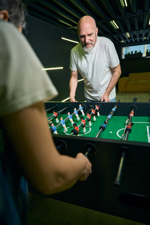 Caucasian man focused on foosball game with friend indoorsの写真素材