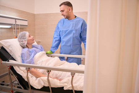 Concerned man with recovering woman in hospital room