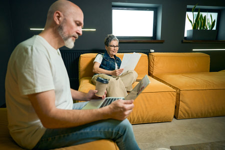 Middle-aged couple working in modern living room with laptop