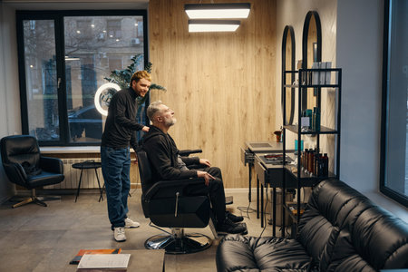 Hairstylist serving male client at barber shop