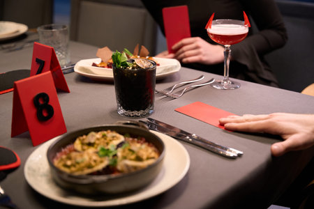 Two adults holding red cards on dimly lit restaurant table