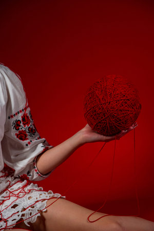 cropped view of woman in embroidery holding ball of yarn isolated on red