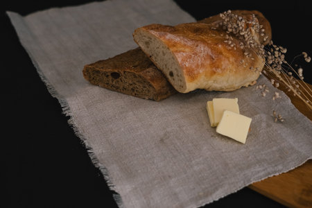 Sliced â€‹â€‹bread lying on a linen cloth on a wooden board. A dry twig lies nearby....
