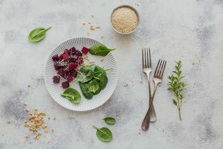 Healthy breakfast with boiled beetroot, baby spinach leaves, pine nuts and sesame seeds on light table.の写真素材