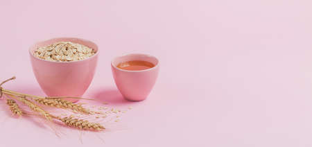 Bowl of dry oat flakes with honey and ears of wheat on light backgroundの写真素材