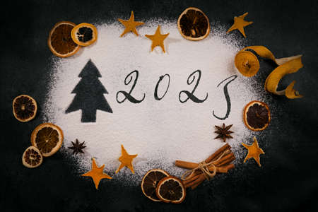 Christmas tree and 2023 drawn on the Scattered Flour on black background, baking accessories and ingredients. Merry Christmas and Happy New Year 2023. Top viewの写真素材