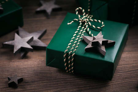 Christmas frame with green gift boxes and wooden star decorations on dark wooden background. Holiday background in natural earth colours.の写真素材