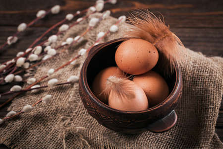 Happy Easter card with natural color eggs, pussy willow branches and feathers on dark wooden backgroundの写真素材