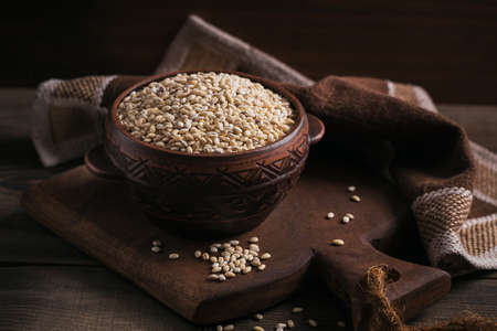 Organic uncooked dried barley cereal grain in a bowl on dark wooden background. Healthy and diet food concept.の写真素材