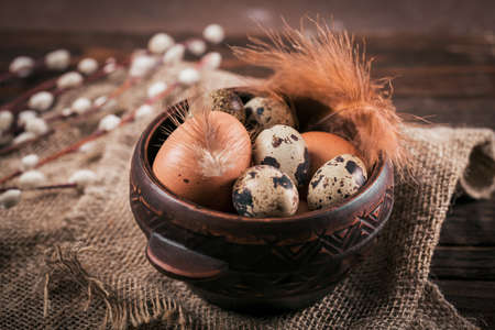 Happy Easter card with natural color eggs, pussy willow branches and feathers on dark wooden...