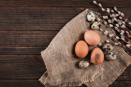 Easter background with natural color eggs, pussy willow branches and brown feathers on beige background. Free space for textの写真素材