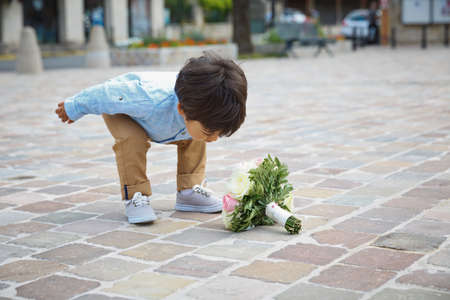 Portrait of a little eastern handsome baby boy playing outdoor with a bouquet of flowers.の写真素材