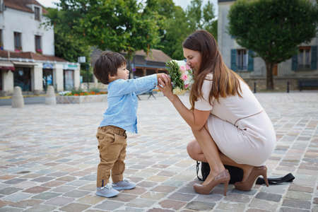 Mixed race boy congratulating his mother and giving her flower bouquetの写真素材