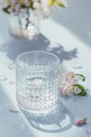 Glass of water on the table with blossoming apple tree branch in a glassの写真素材